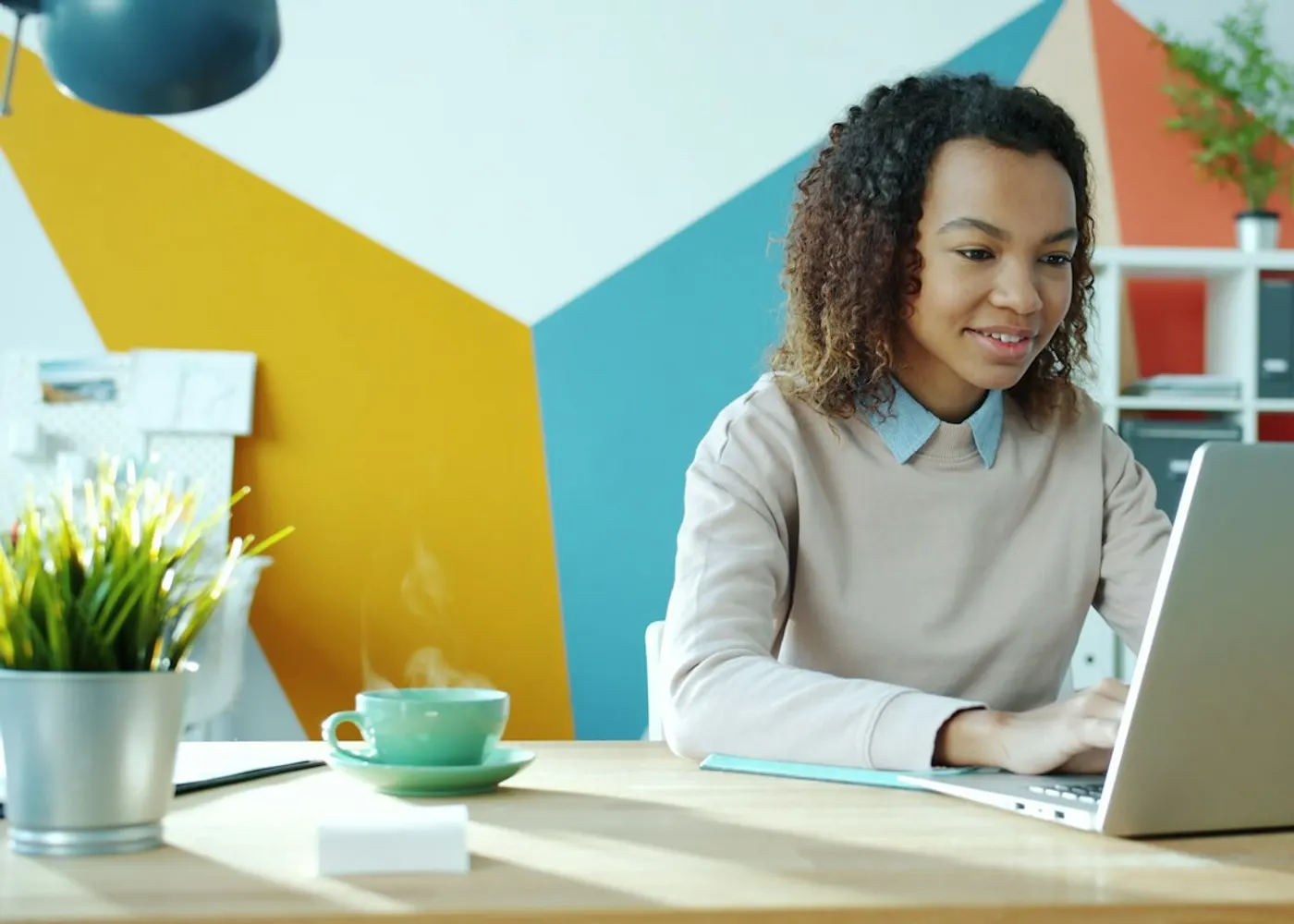 A young woman smiling as she works on her laptop